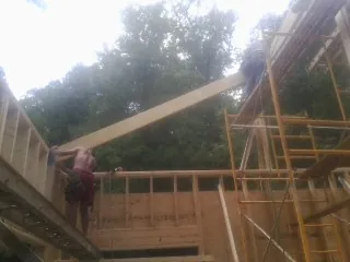 Carpenter raising a rafter beam on a new second story frame in Ferndale