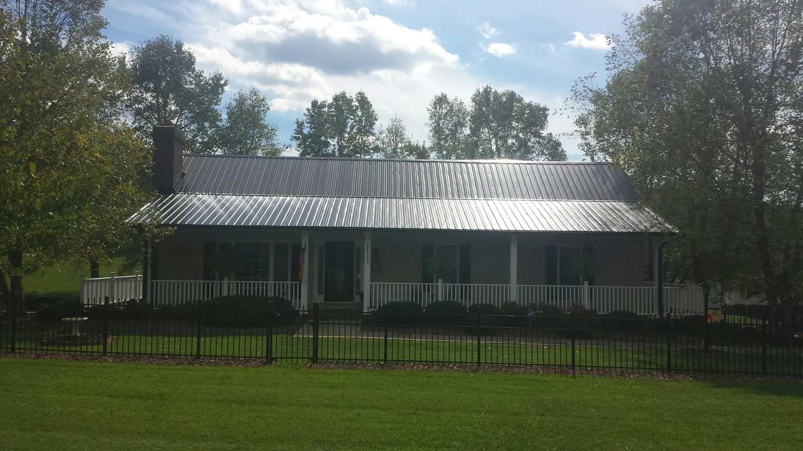 Gray metal roof on a brick ranch with a full width front porch — Gutter Guard Installation work by our crew in Ferndale